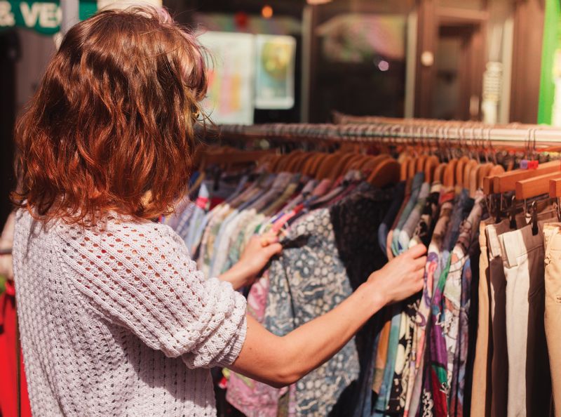 Young woman shopping second-hand clothes rail