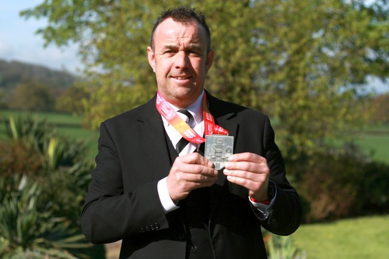 Julian Goodwin outside Sue Ryder Leckhampton Court with his London Marathon 2018 finisher’s medal