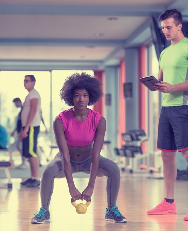Woman at gym with male personal trainer exercise