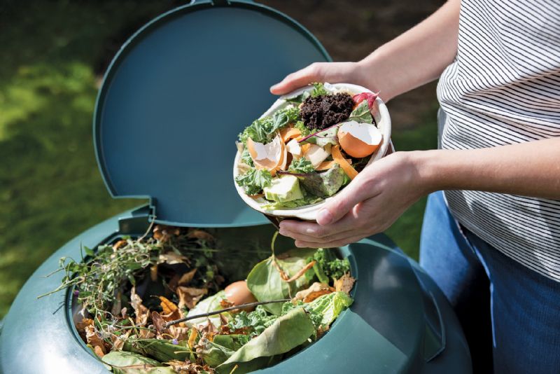 Woman putting food in compost bin garden